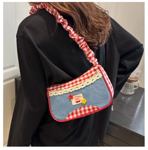 Detail view of denim shoulder bag featuring red plaid trim and white lace edge decoration