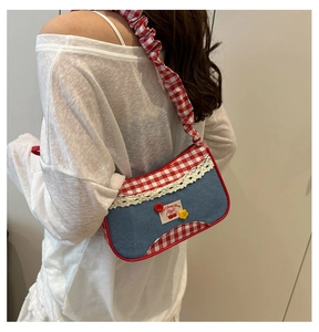 Detalle de bolso vaquero azul con borde de cuadros rojos y parche de cereza dulce