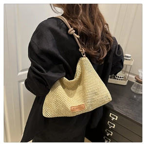 Detail of hand-woven straw tote with brown leather strap and FASHION logo tag