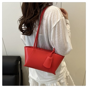 Détail du sac cabas en cuir synthétique rouge porté par un mannequin avec étiquette