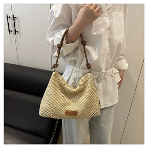 Close-up of hand-woven beige tote bag featuring knotted brown leather handle detail