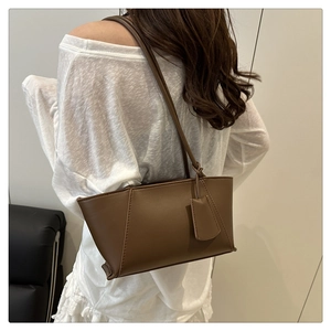 Detail of brown baguette shoulder bag with smooth faux leather finish and visible stitching
