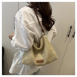 Detail of woven straw tote bag with brown leather tag and adjustable knot straps