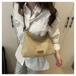 Macro detail of hand-woven straw tote bag with brown leather patch and knot strap