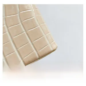Detail shot of the cream-colored croc-embossed leather texture on a trendy crossbody bag