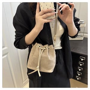 Dettaglio della borsa a secchiello in velluto beige con coulisse e tracolla in pelle