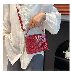 Detail of red crocodile texture bucket bag featuring a silver V-shaped metal buckle clasp