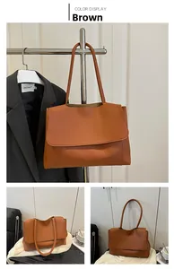 Detail view of brown faux leather tote bag with large flap and slim straps on a suit