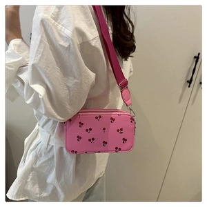 Model wearing a pink cherry print crossbody box bag with wide fabric shoulder strap