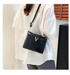Detailed side view of a black crocodile pattern bucket bag with golden V-shaped logo