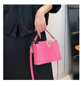 Detailed view of rose pink crocodile pattern handbag with golden metal V logo and slim strap