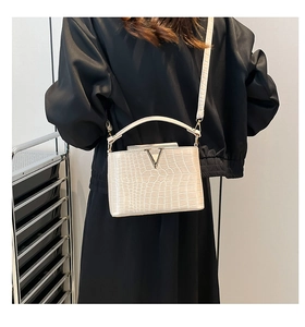 Detail of cream crocodile embossed texture on a tote bag with silver V-shaped hardware