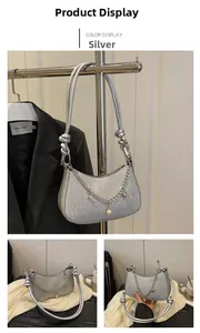 Détail d'un sac à main argenté à paillettes avec chaîne en métal et pendentif perle