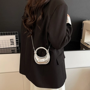 Mini bolso plateado de espejo en forma de medialuna con cadena sobre chaqueta negra