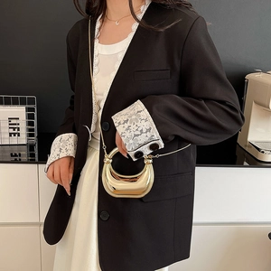 Elegante bolso de media luna dorado metalizado con cadena acrílica sobre fondo negro