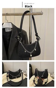 Détails du sac noir à paillettes avec charms argentés et bandoulière à nœuds