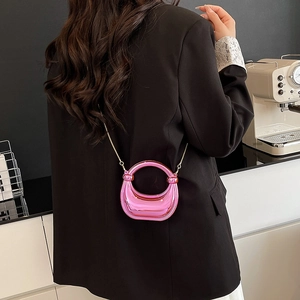 Minibolso de fiesta rosa metalizado con asa redonda y cadena dorada sobre modelo