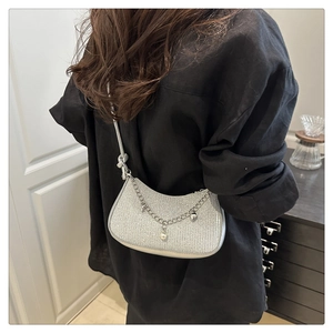 Detail of silver crescent shoulder bag with metallic chain and pearl drop charm