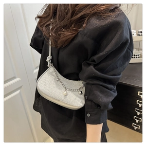 Silver glittery hobo bag with pearl and heart pendant shown on shoulder