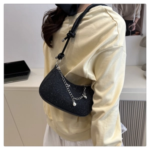 Détail du sac sous l'aisselle à paillettes noires avec chaîne perle et bandoulière corde