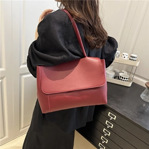 Minimalist burgundy PU leather tote bag with large flap shown on model's shoulder
