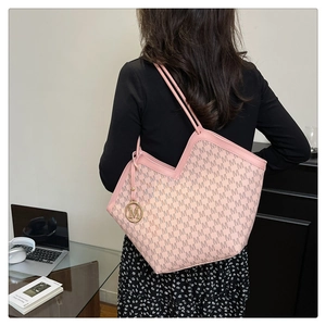 Sac fourre-tout rose imprimé de lettres avec pendentif M en métal dans un bureau