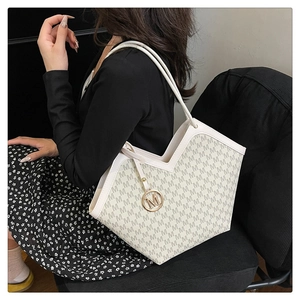 Détail du sac seau beige avec motif M répété et pendentif en métal doré chic