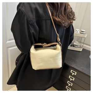 Detail of cream corduroy crossbody bag featuring vertical texture and brown strap on model