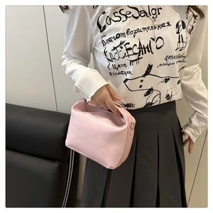 Detail of light pink pleated handbag with metal ring handle worn with casual outfit