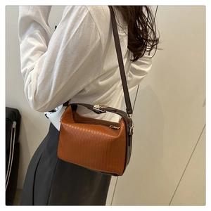 Close-up of pleated leather shoulder bag in caramel brown with metallic gold clasp detail