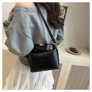 Chic black pleated shoulder bag with gold hardware and elegant vertical textures