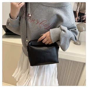 Detail of black pleated texture shoulder bag with elegant gold metal hardware buckle