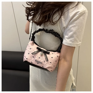 Detail of pink bow shoulder bag with heart pendant and ruffled fashion handle