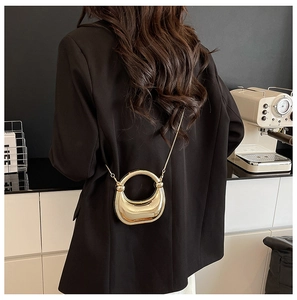 Detail of a mini gold metallic crescent handbag with an elegant shoulder chain strap
