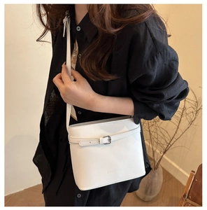 Détail du sac seau blanc en cuir avec boucle métallique et logo de marque embossé
