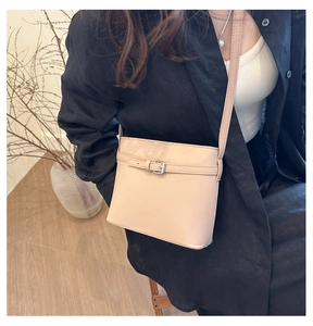 Detail of beige litchi pattern bucket bag with strap buckle and branded embossed logo