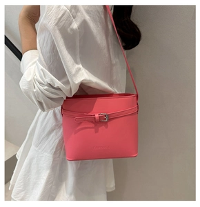 Detail of a bright pink leather bucket bag with metallic buckle and embossed logo