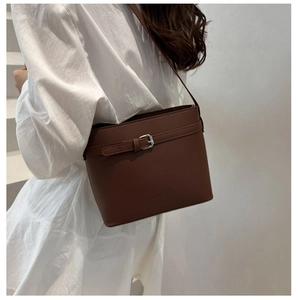 Detailed view of deep brown leather bucket bag with silver buckle and embossed logo