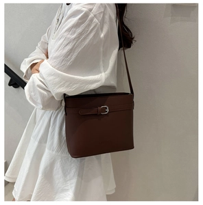 Detail of dark brown leather bucket bag with silver metal buckle and branded logo