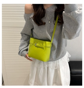 Detail of lime green leather handbag featuring belt buckle decor and embossed brand logo