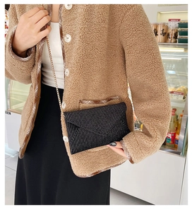 Detailed view of black rhinestone envelope crossbody bag with a gold metal chain strap