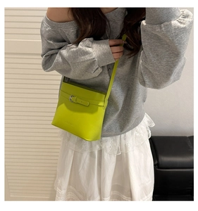 Close-up of vibrant lime green bucket bag with silver buckle and embossed logo detail