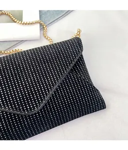 Close-up of black envelope clutch with shimmering rhinestones and a gold chain strap