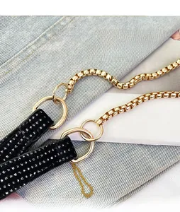 Detail of gold box chain and sparkling rhinestone strap with metallic ring connector