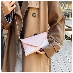 Pink envelope glitter bag with golden chain strap worn by a model on a sunny terrace