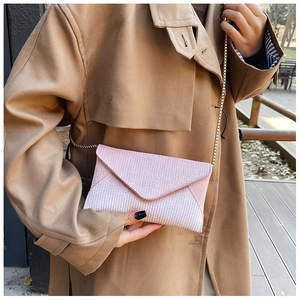 Close-up of pink glitter envelope clutch bag with gold chain strap on trench coat