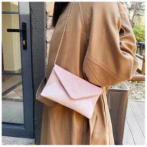 Pink sequin envelope clutch bag with gold chain strap shown on camel wool coat