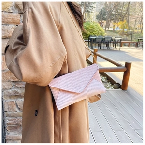 Pink envelope crossbody bag with textured fabric and gold chain strap on a model