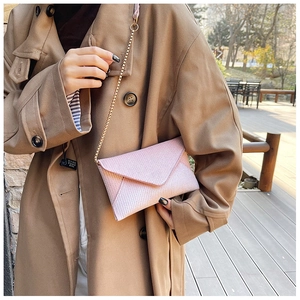 Detailed view of pink woven envelope bag with gold bead chain strap and metal texture