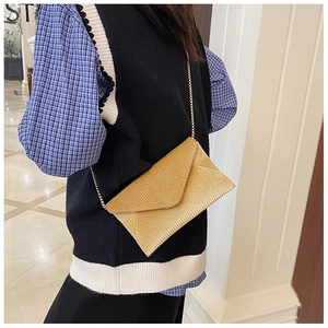 Close-up of golden glitter envelope bag with fine metal chain strap on model's side